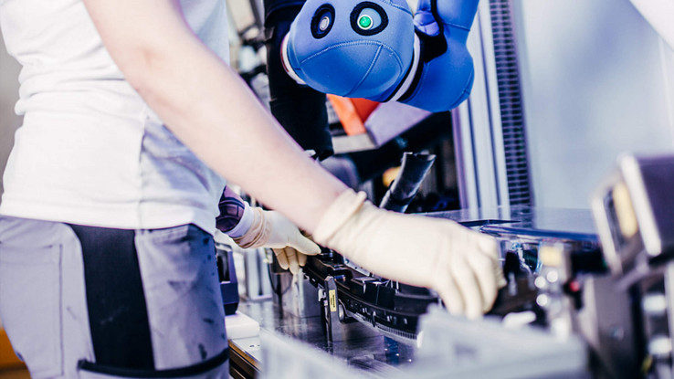 Kollaborierende Roboter COBOTs, also kollaborierende Roboter, arbeiten gemeinsam mit den Montagemitarbeitern am Fertigungsband.